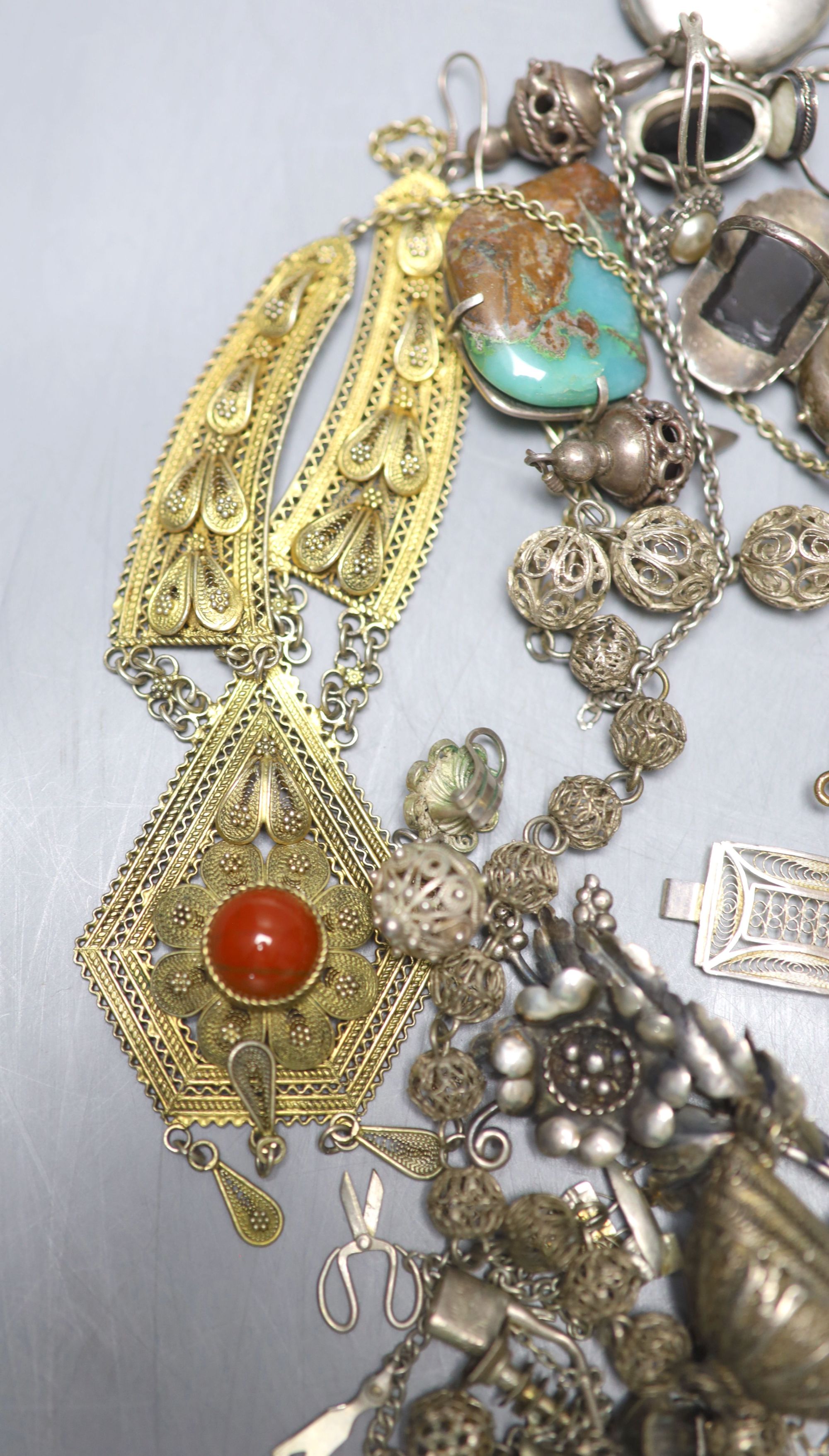 A mixed group of assorted white metal and costume jewellery including locket, brooches and filligree items.